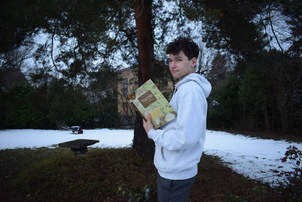 Junger Mann mit braunen Locken im grauen Pullover im Garten hält das Buch Narnia von C. S. Lewis 

Beitrag: Wie funktioniert Legimi?