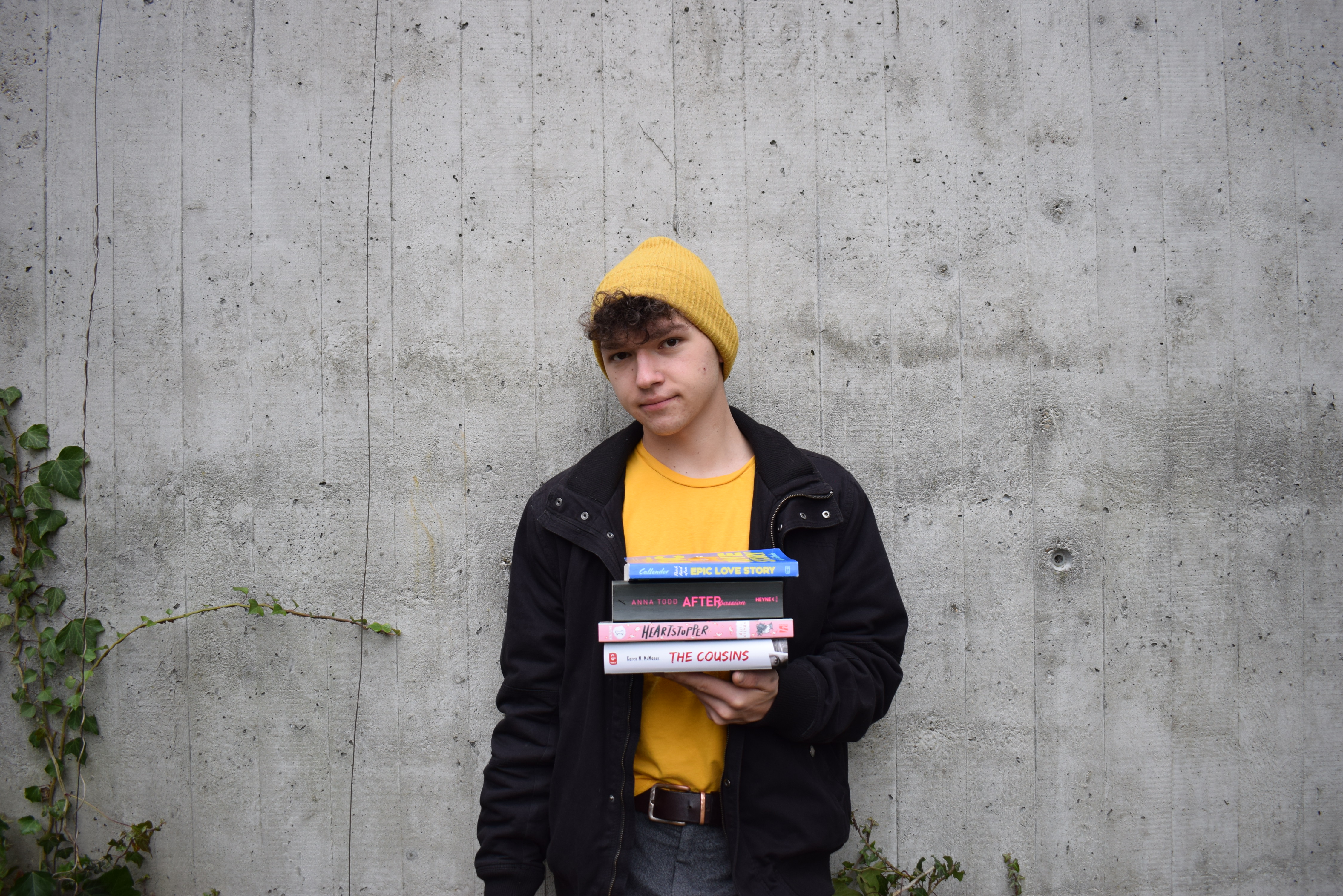 Monatsrückblick Januar 2021 - Josia Jourdan - young man in a yellow shirt, with a yellow beanie holding a stack of books in his hands