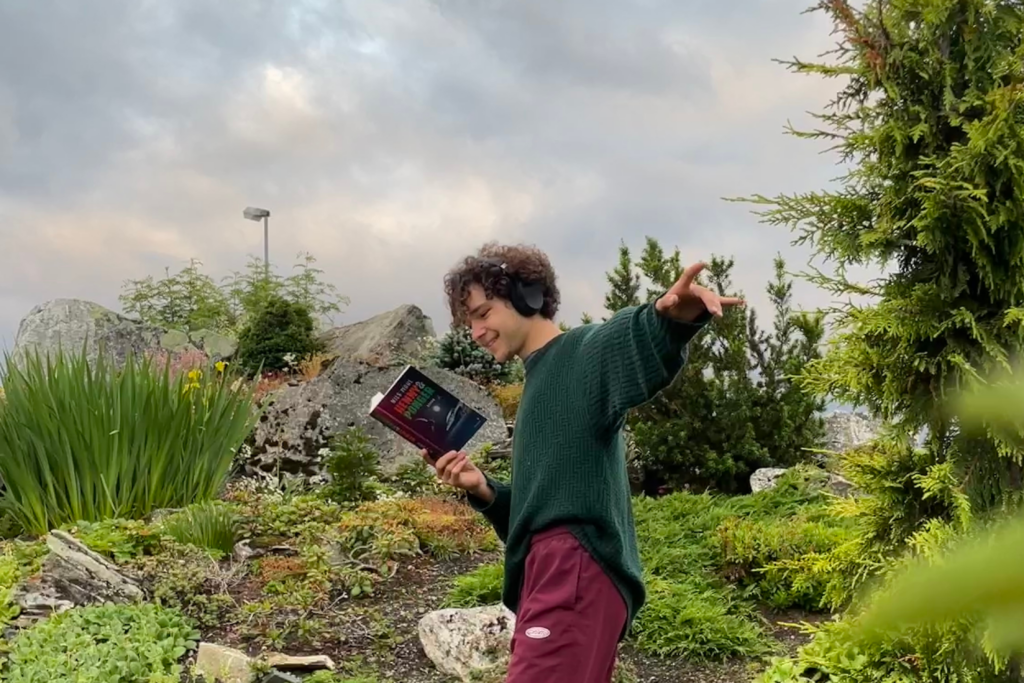 junger Mann liest ein Buch - Henny und Ponger von Nils Mohl - in der Natur
